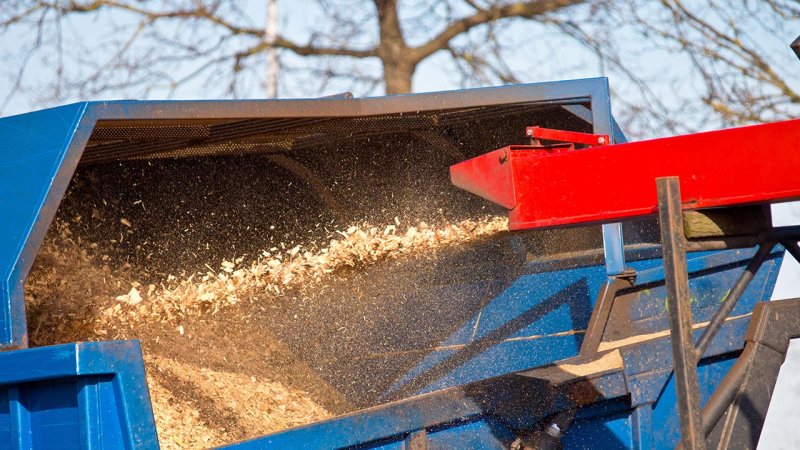 The chute of a wood chipper expelling processed wood waste. (Source: © creativenature.nl / stock.adobe.com)