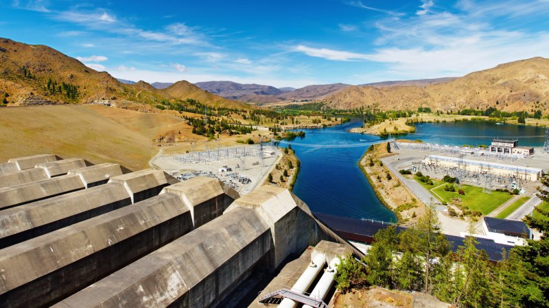 Sizable concrete penstocks are used to feed water to the powerhouse of the Benmore power plant, New Zealand. Further away we can see transformers and power lines. (Source: © Dmitry Pichugin / stock.adobe.com)